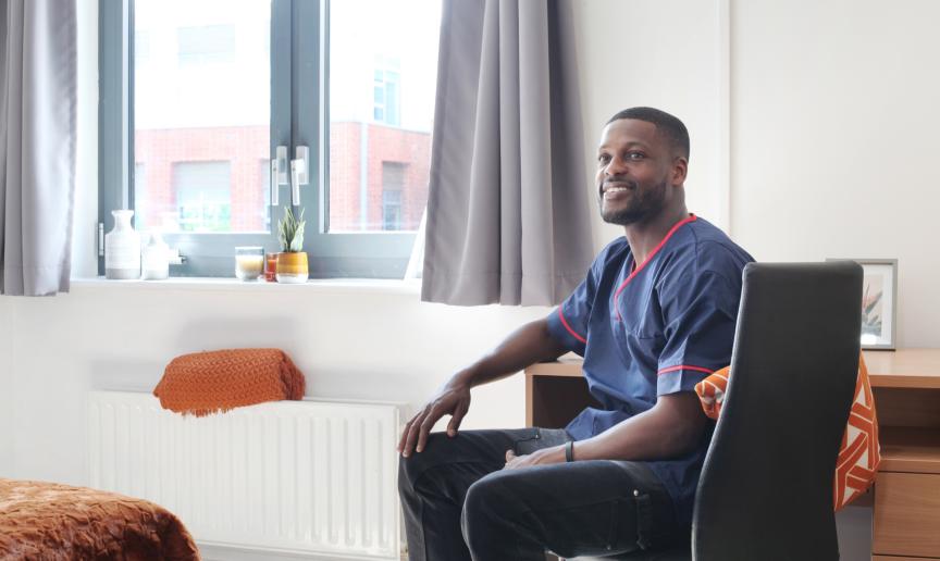 A male resident of Broomfield, sat on the desk chair in his room smiling