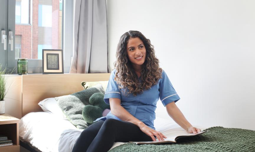 A female resident of Colchester accommodation sat on the bed in her room